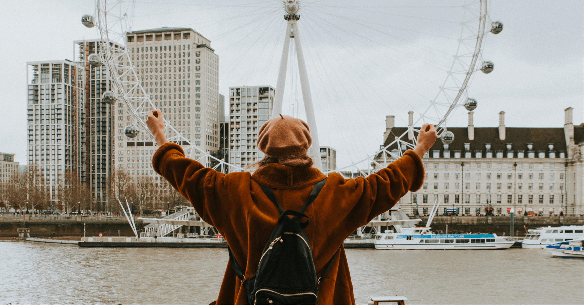 Girl with arms raised infront of the London Eye